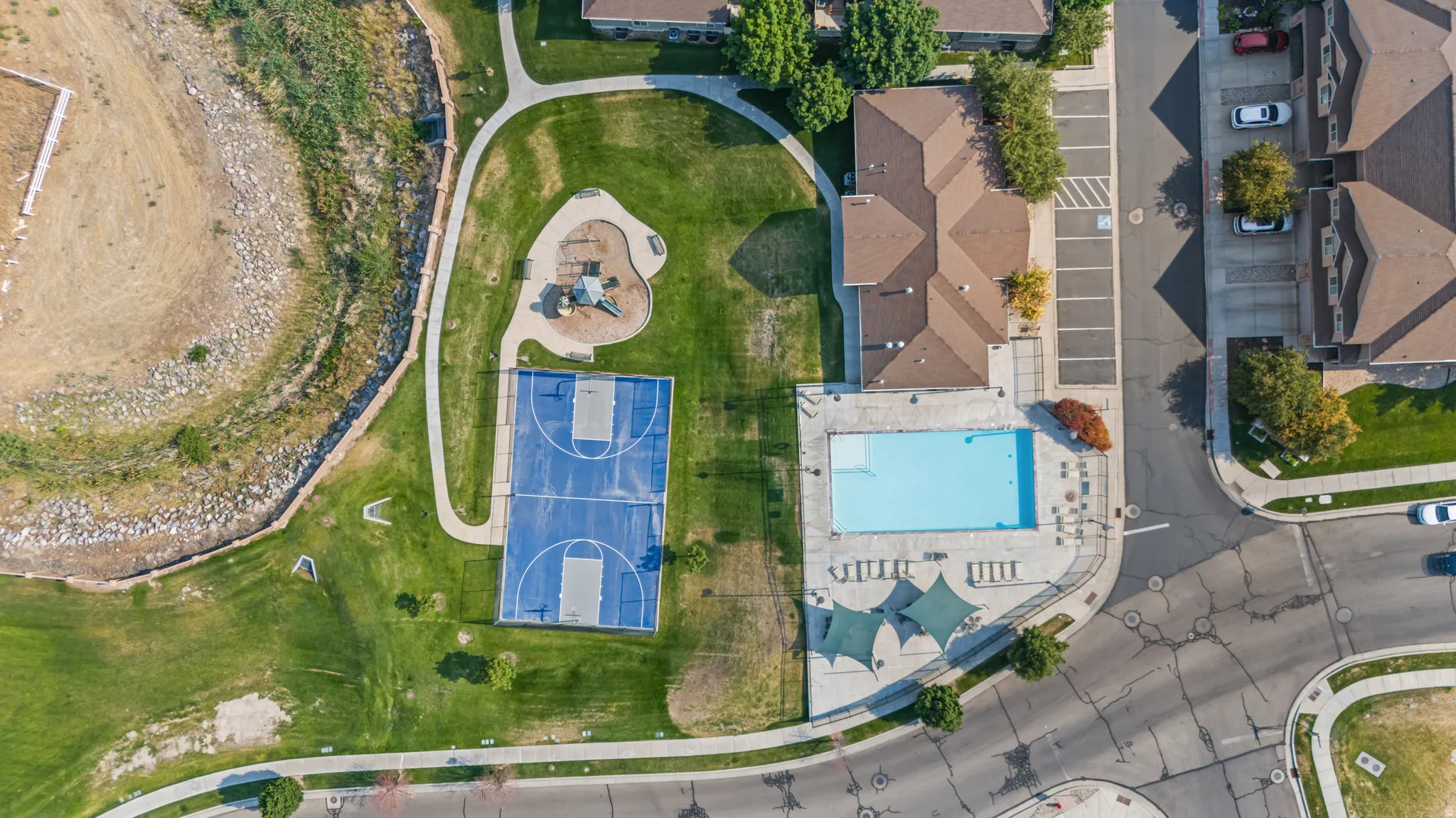 Community amenities featuring a swimming pool, basketball court, and playground surrounded by green spaces and paved pathways