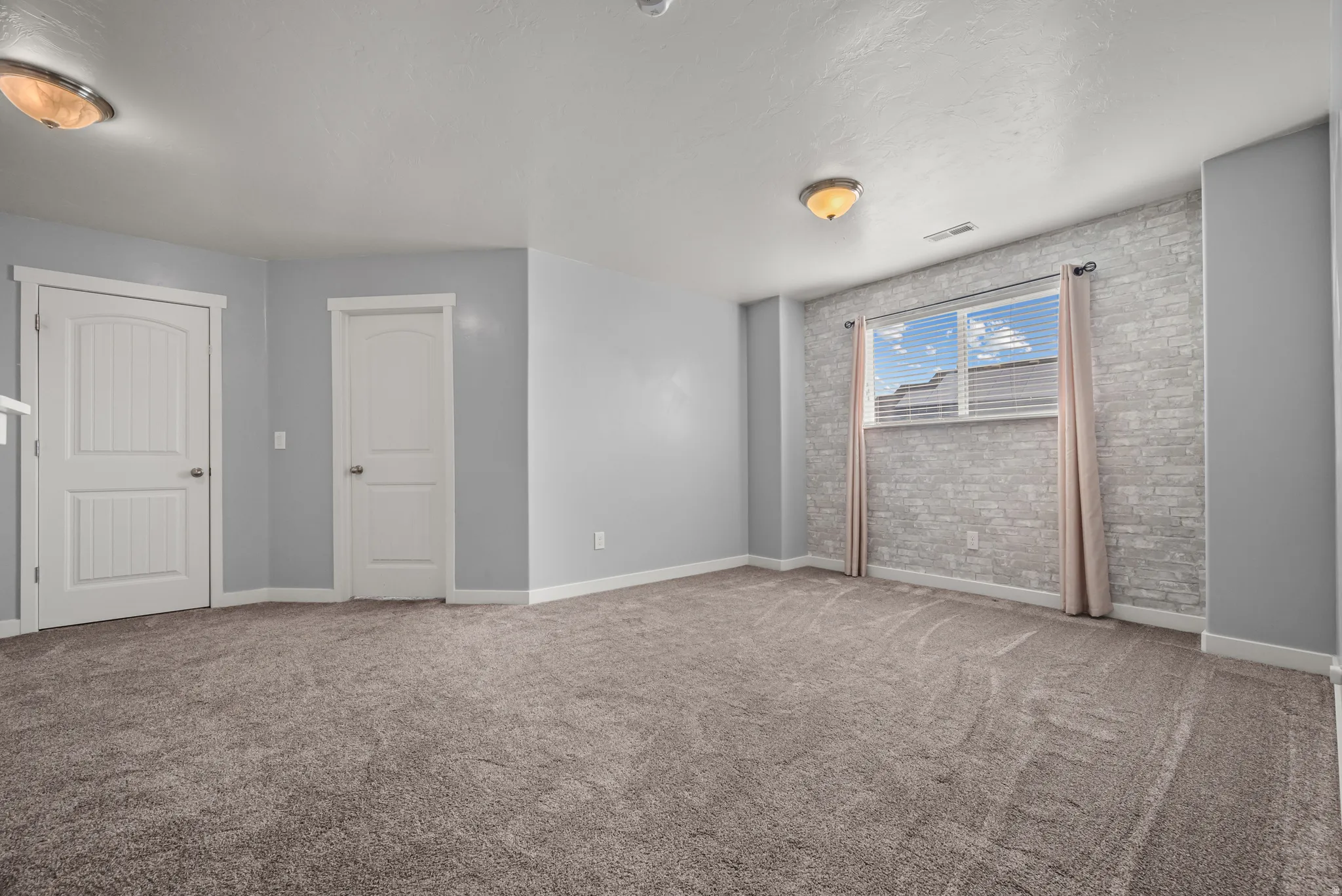 Spacious room featuring plush carpet flooring, two paneled interior doors, and a window with blinds