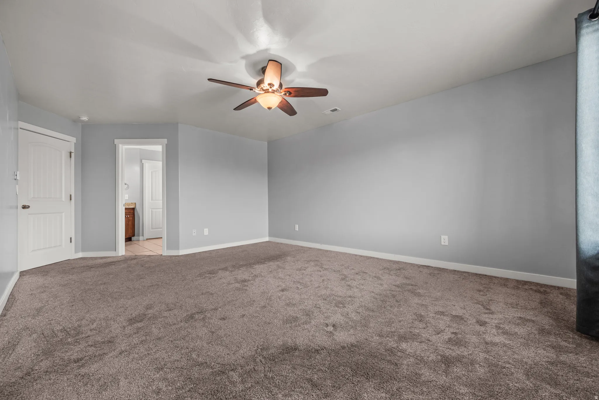 Spacious room featuring neutral grey walls and plush carpeting