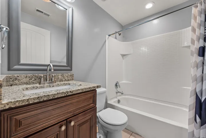 Bathroom featuring a wood-finish vanity with a granite countertop, undermount sink, and brushed nickel faucet