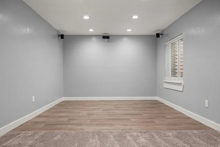 Versatile bonus room featuring recessed lighting, wall-mounted speakers, wood-finish flooring, and a window with blinds