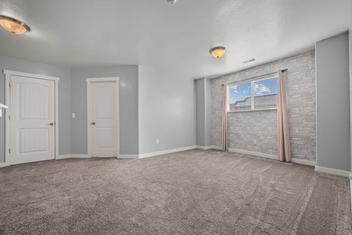 Spacious room featuring plush carpet flooring, two paneled interior doors, and a window with blinds