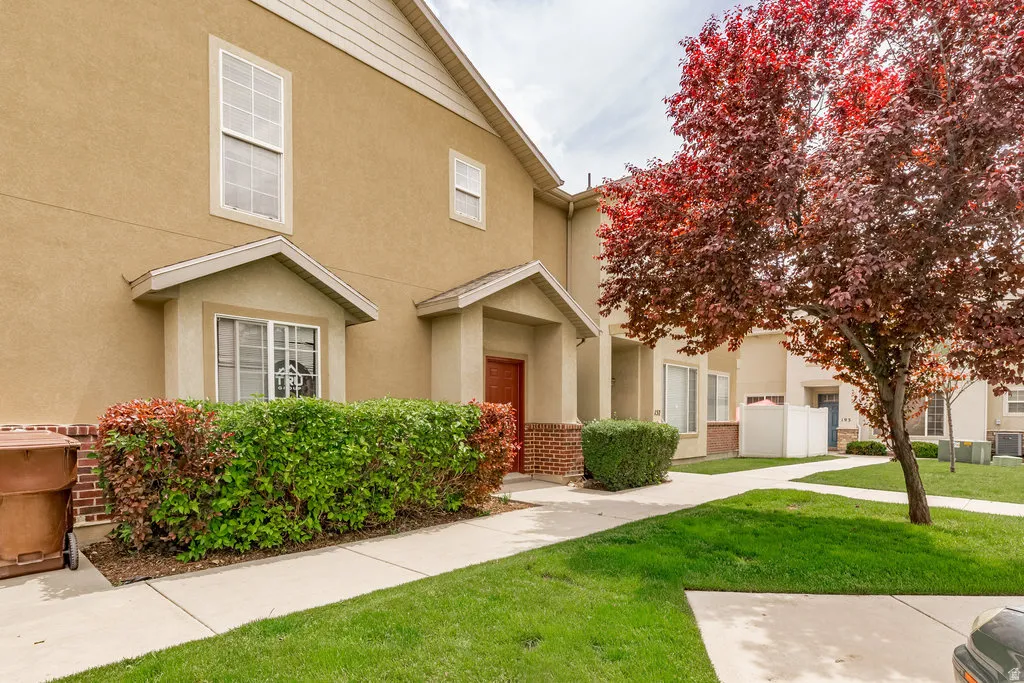 Townhome exterior featuring tan stucco siding, brick accents, and a covered entry