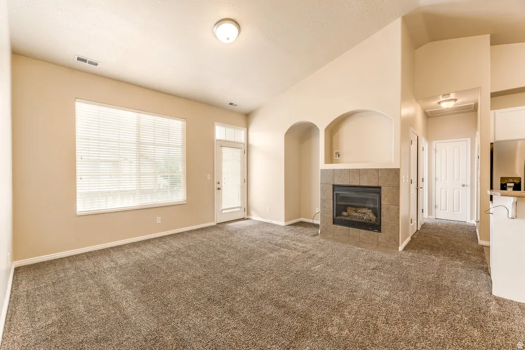 Living area featuring vaulted ceilings and neutral-toned carpet