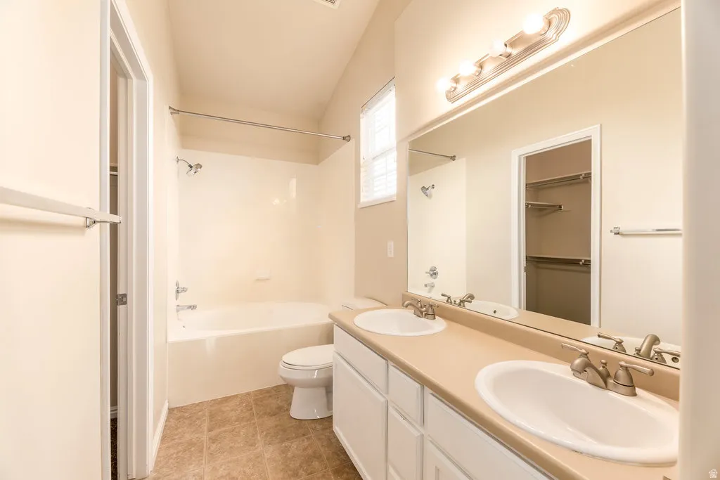 Bathroom featuring a dual vanity with undermount sinks, a large mirror, and a combination shower and tub