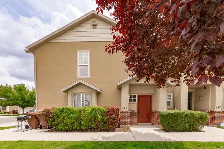 Stucco exterior featuring a covered entry with a red door and brick accents