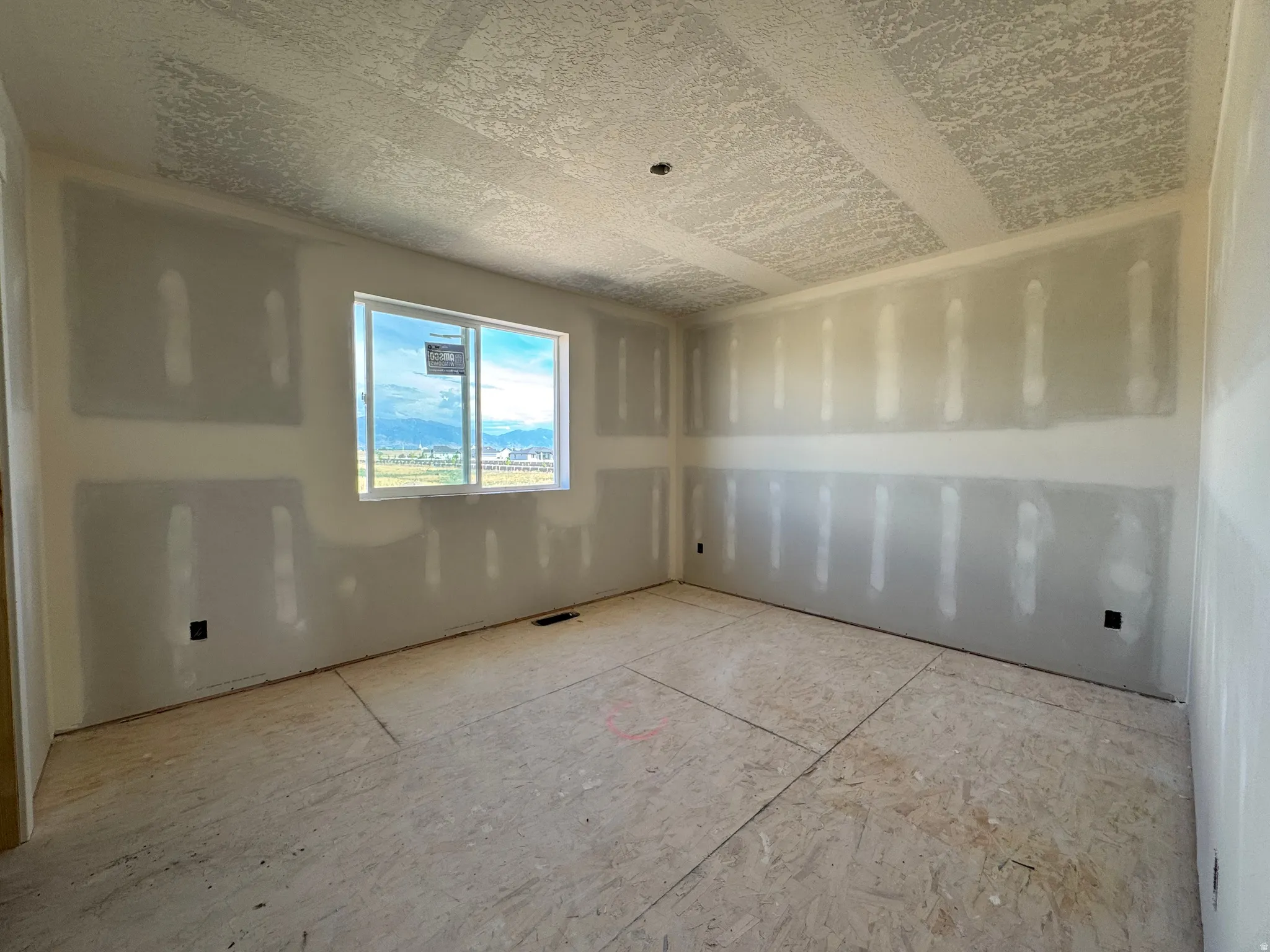 Unfinished interior space with drywall installation, exposed subfloor, and a multi-pane window
