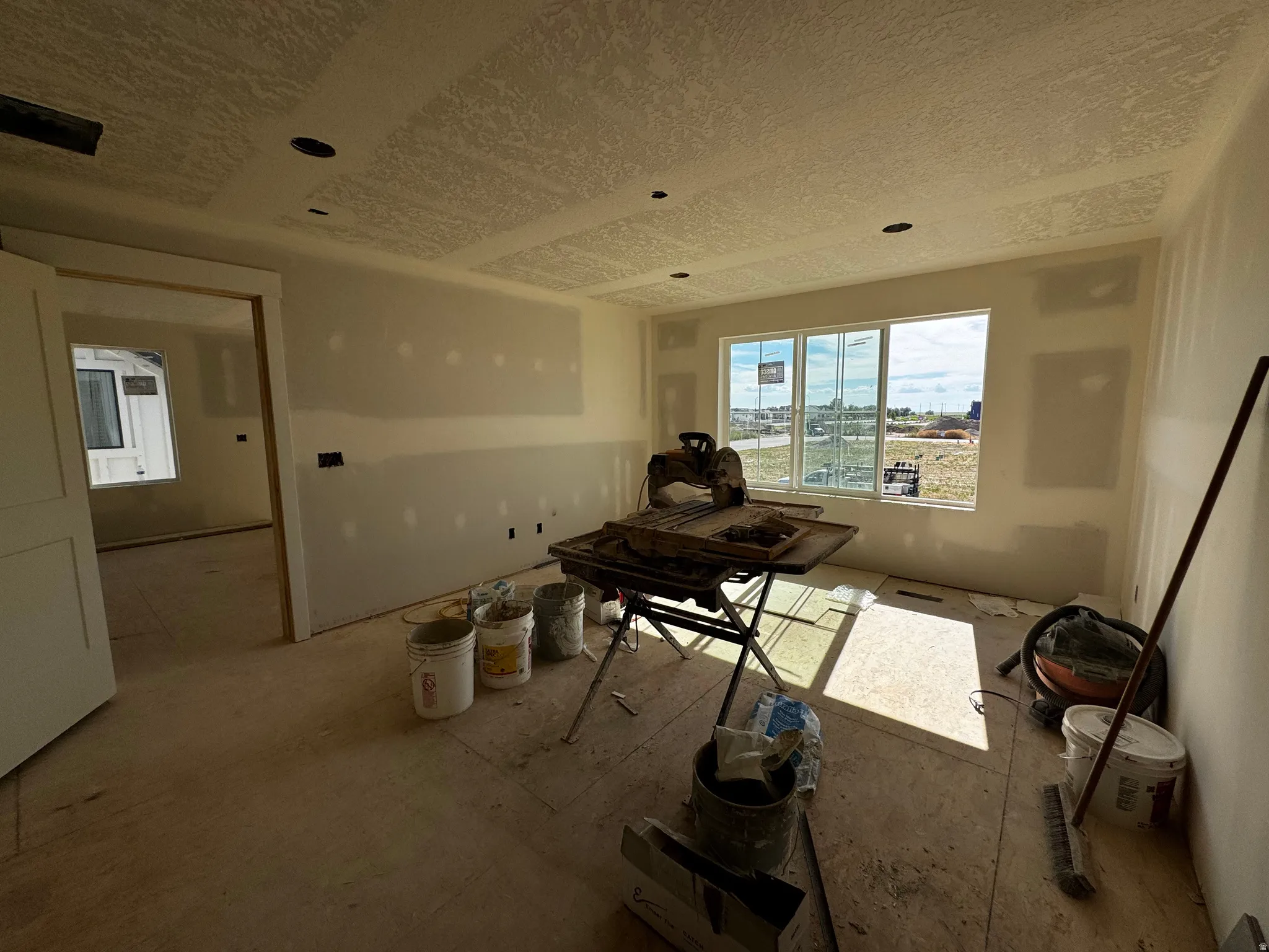 Spacious room under construction featuring multiple windows, recessed lighting, and a textured ceiling