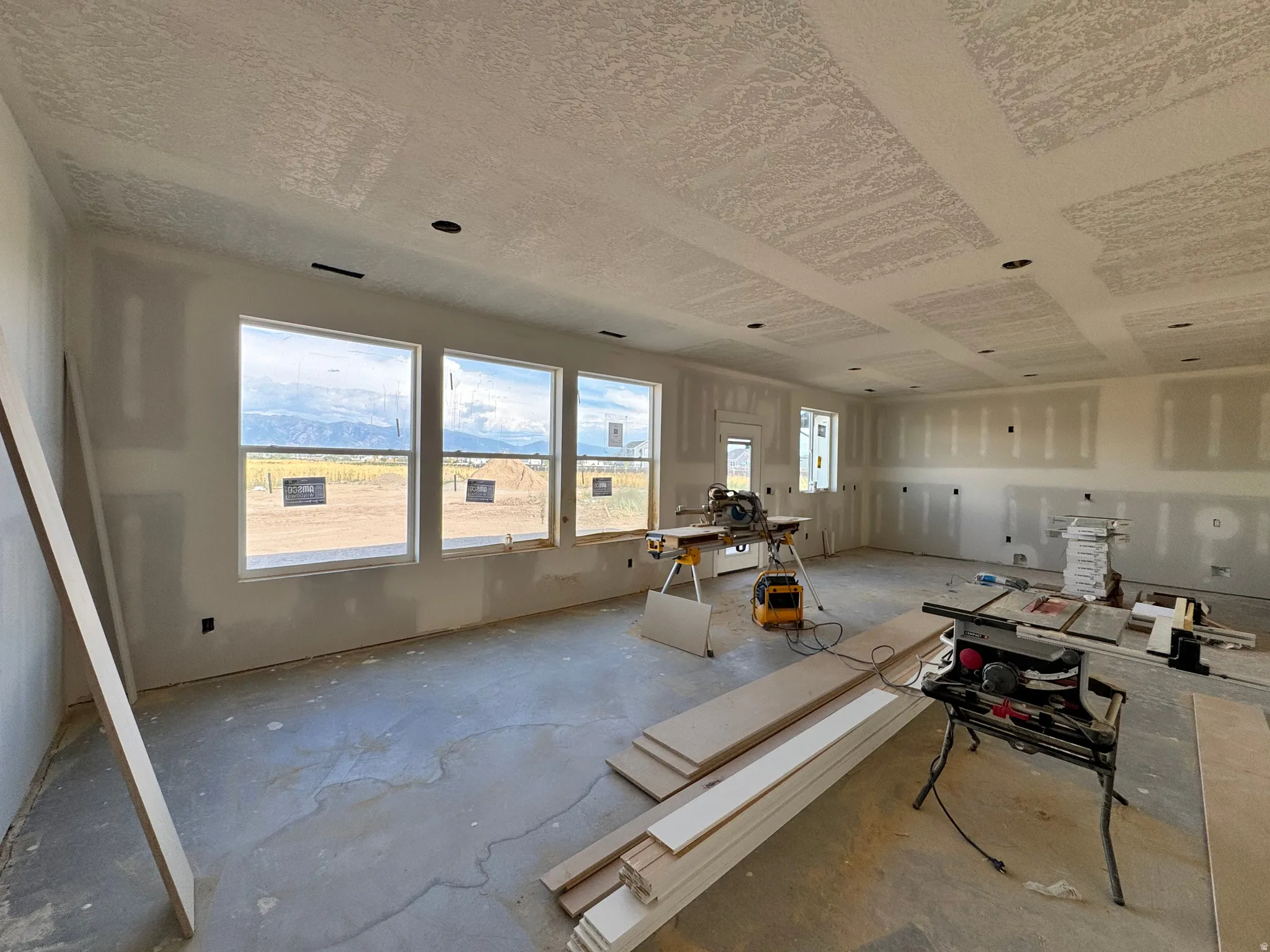 Spacious interior with multiple large windows, recessed lighting preparations, and a textured ceiling finish