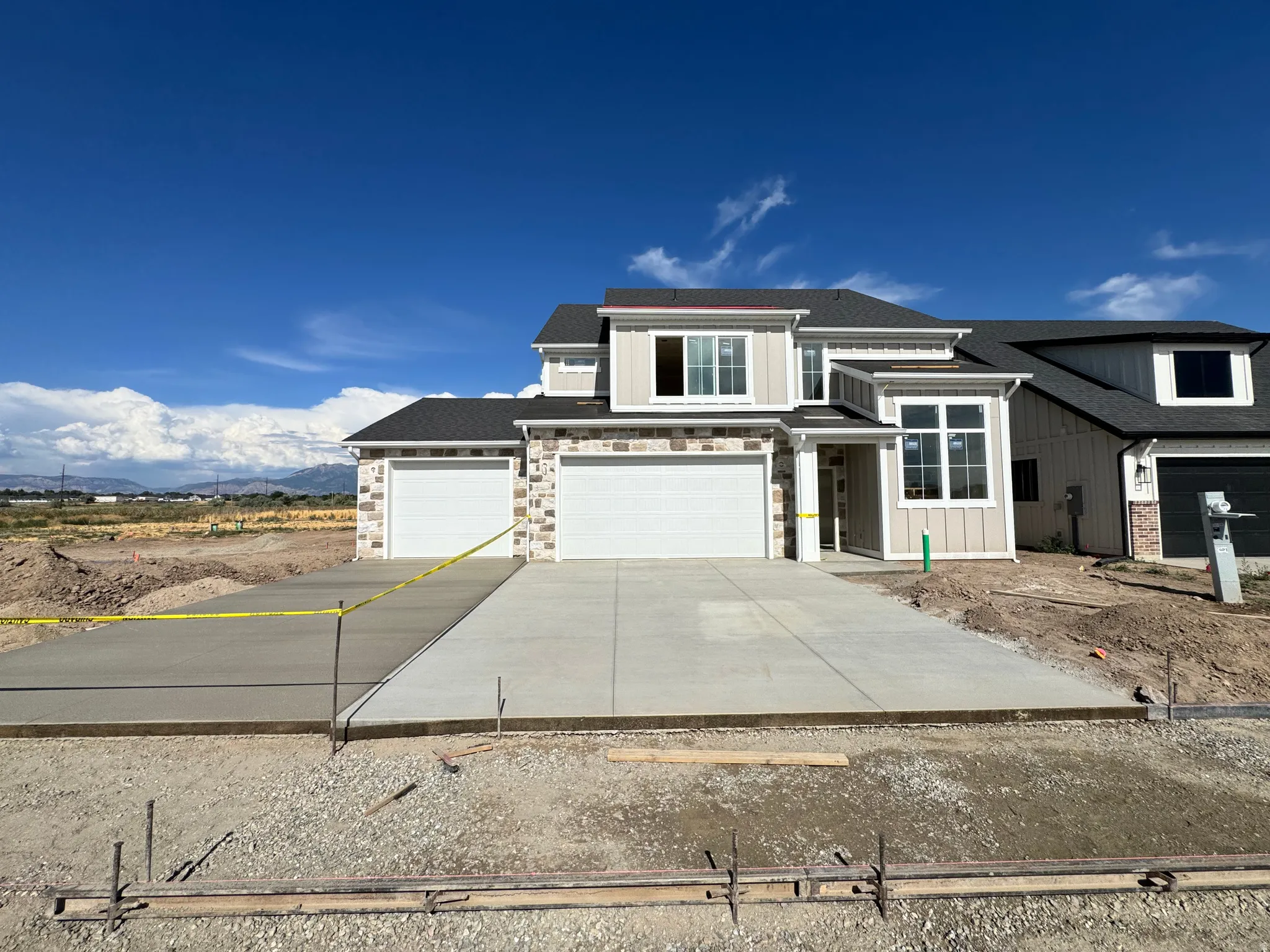 Contemporary home featuring a dual two-car garage, stone and vertical siding exterior, and a prominent entry