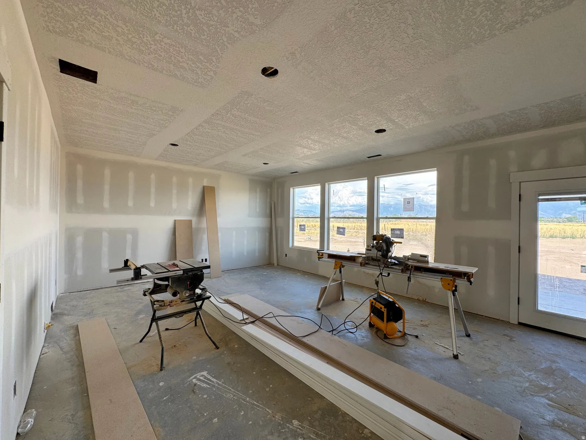 Spacious interior featuring multiple windows, a rear exterior door, and a textured ceiling