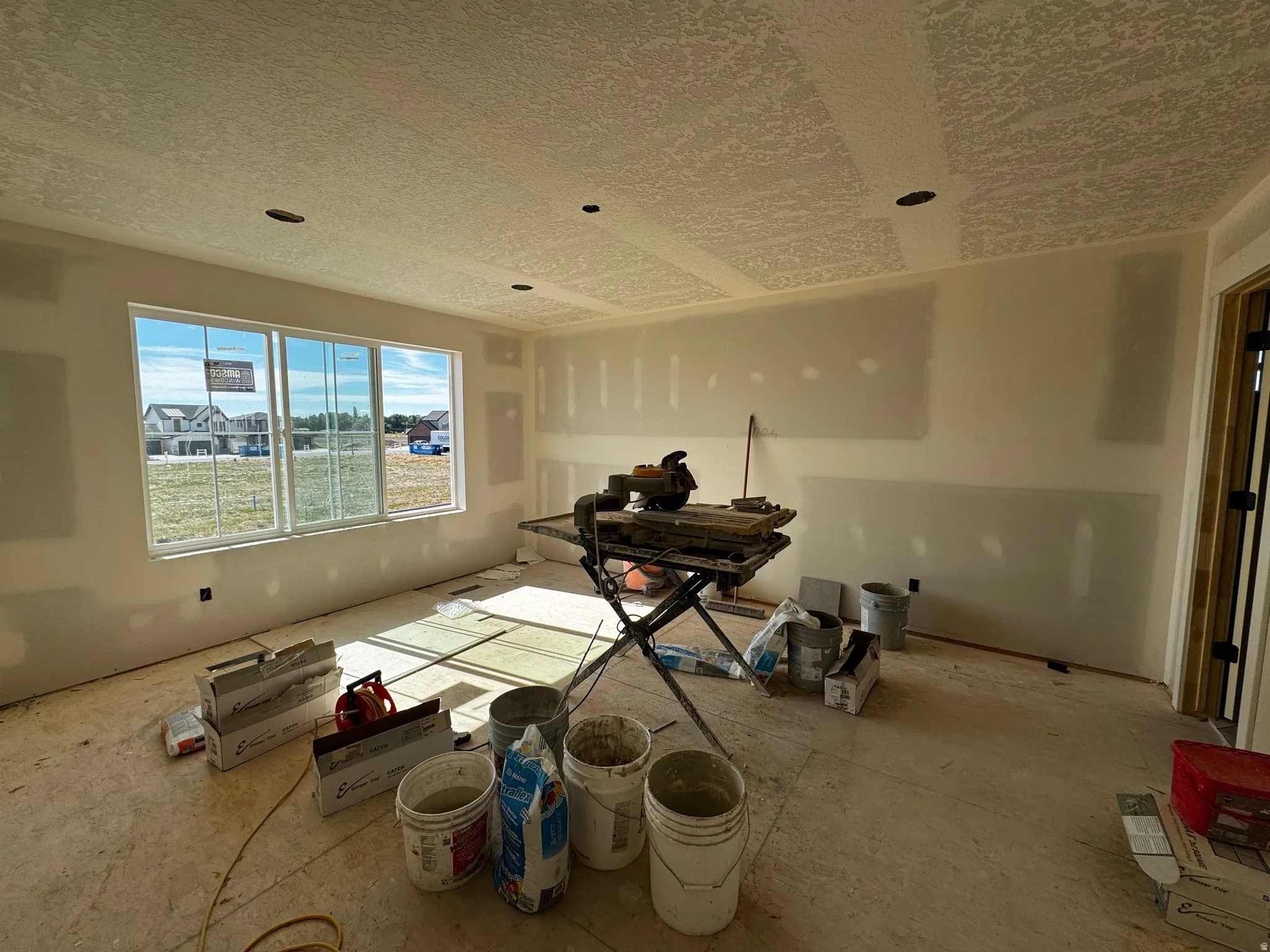 Spacious room featuring multiple large windows, recessed ceiling lighting, textured ceiling, and an open doorway