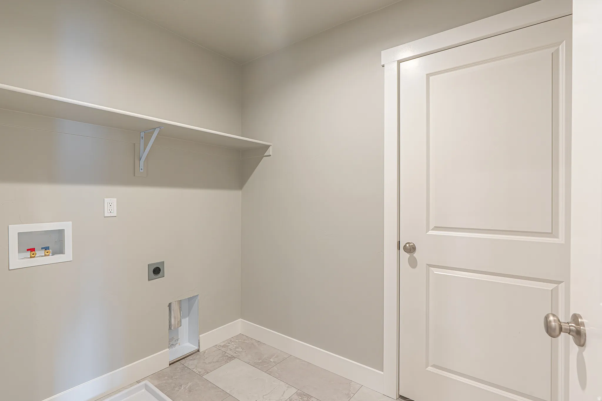 Dedicated utility space featuring a built-in shelving unit, neutral wall paint, and tile flooring