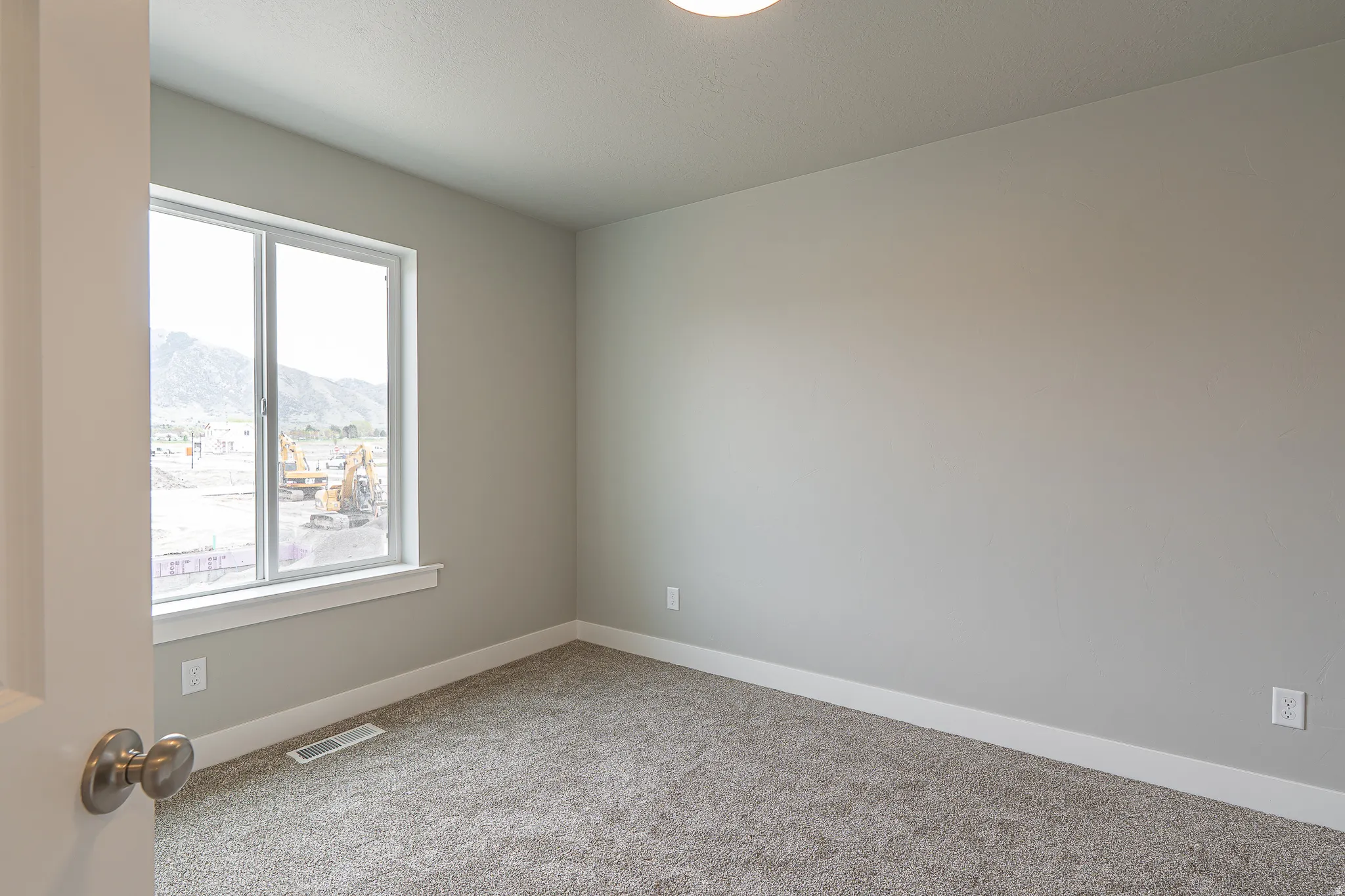Neutral tone wall finishes, gray carpeting, and white trim