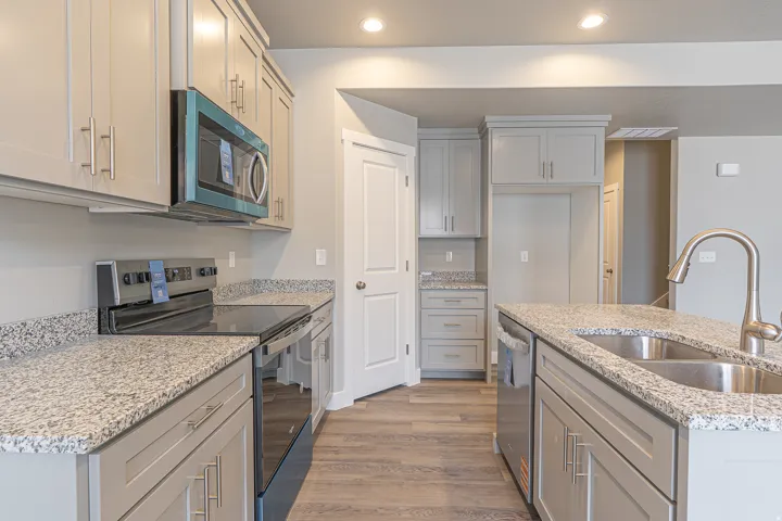 Modern kitchen featuring light gray cabinetry, granite countertops, and wood-finish flooring