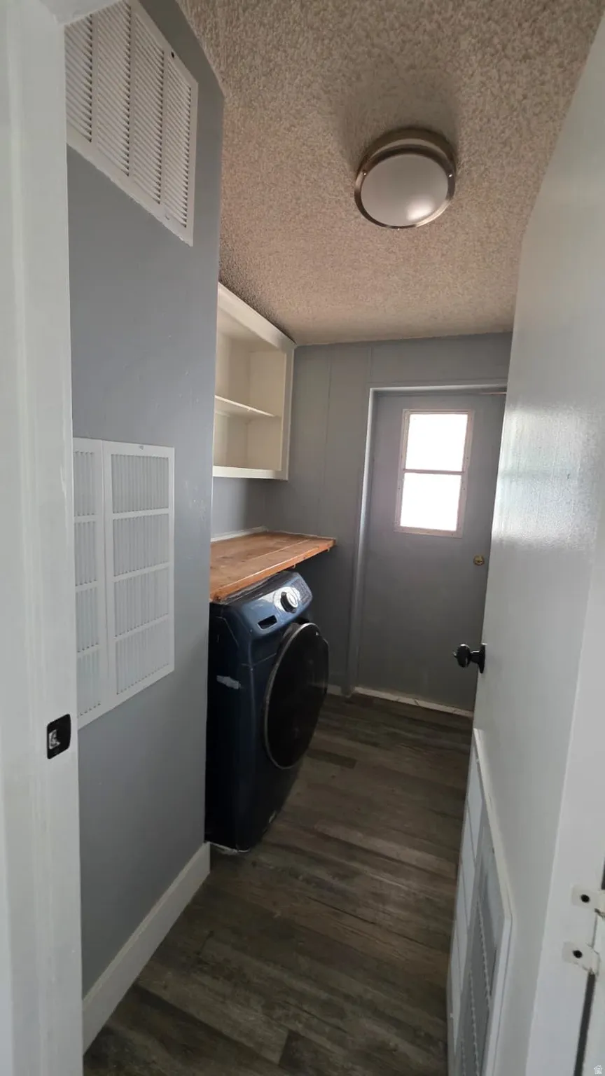 Utility area featuring wood-finish flooring, light gray walls, built-in shelving, a wood-finish countertop, and a rear exterior door with a window
