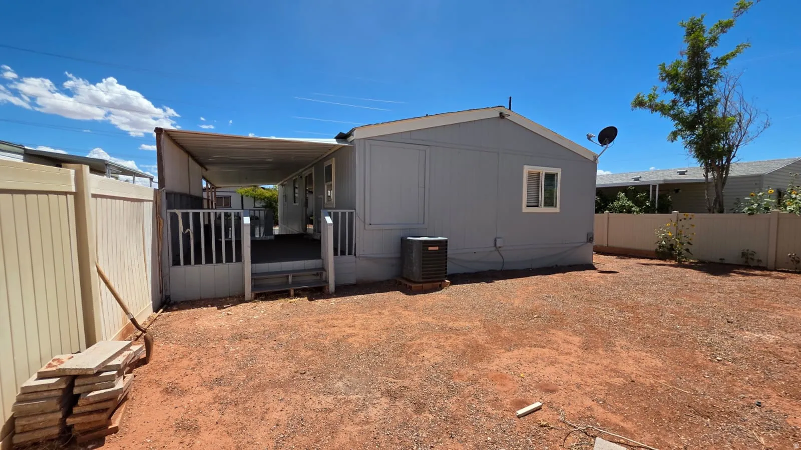 Expansive backyard featuring a covered patio, privacy fencing, and an external HVAC unit