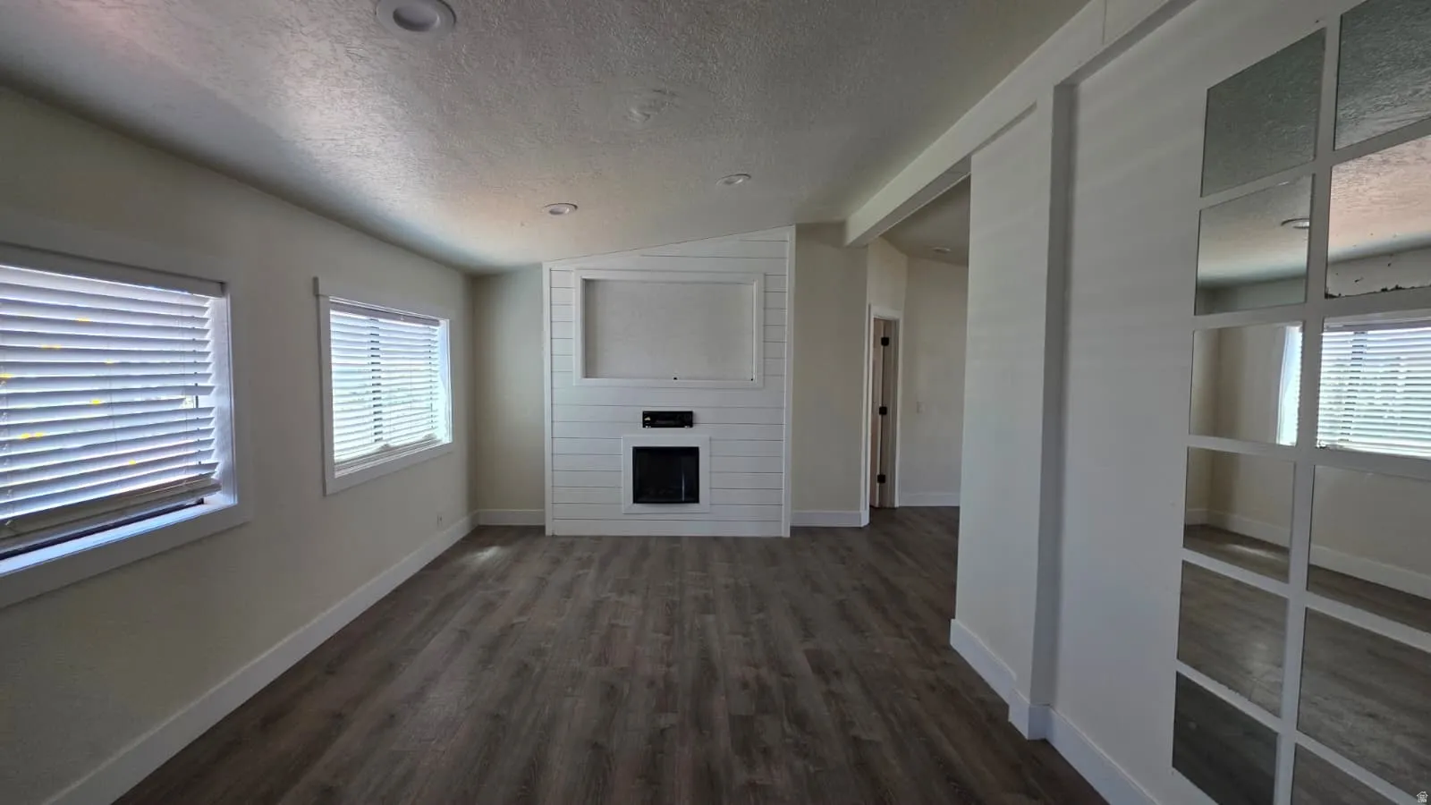 Living area featuring wood-finish flooring and a contemporary fireplace with a shiplap surround