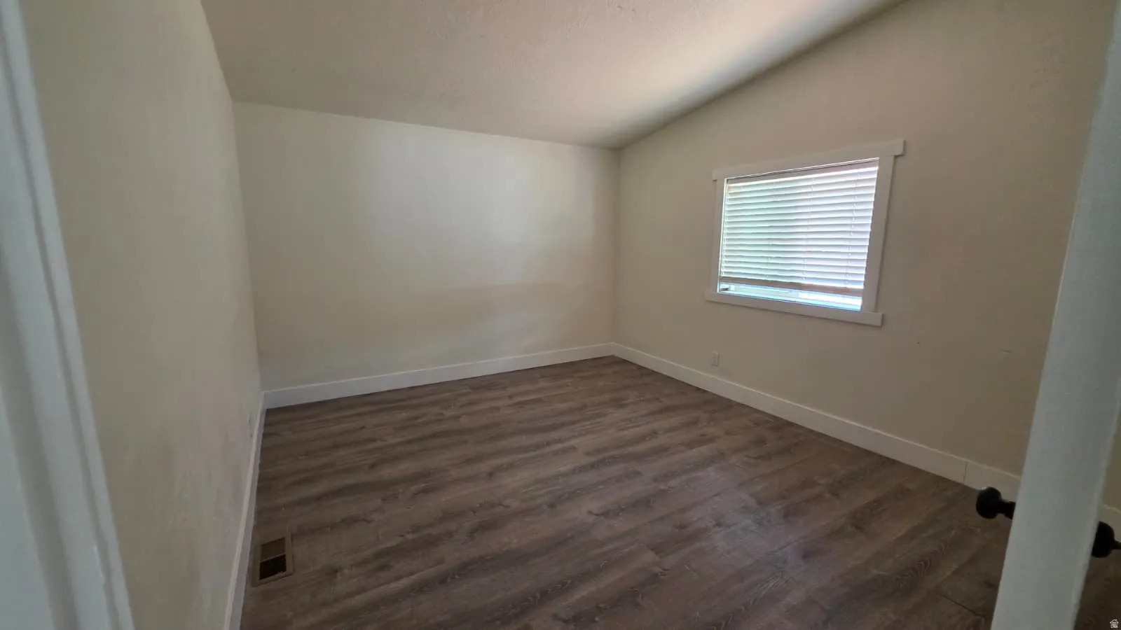 Room with wood-finish flooring, neutral wall paint, white trim, and a window with blinds