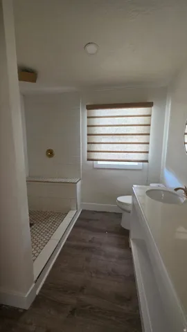 Contemporary bathroom featuring a walk-in shower with a built-in bench, hexagon floor tiling, and a brass-finish shower fixture