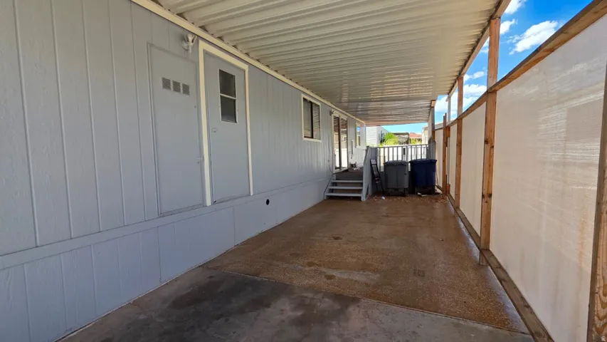 Covered carport with light gray siding and two entry doors