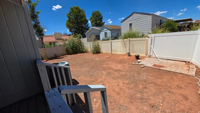 Spacious backyard featuring an exposed earth surface and a partial concrete paver patio