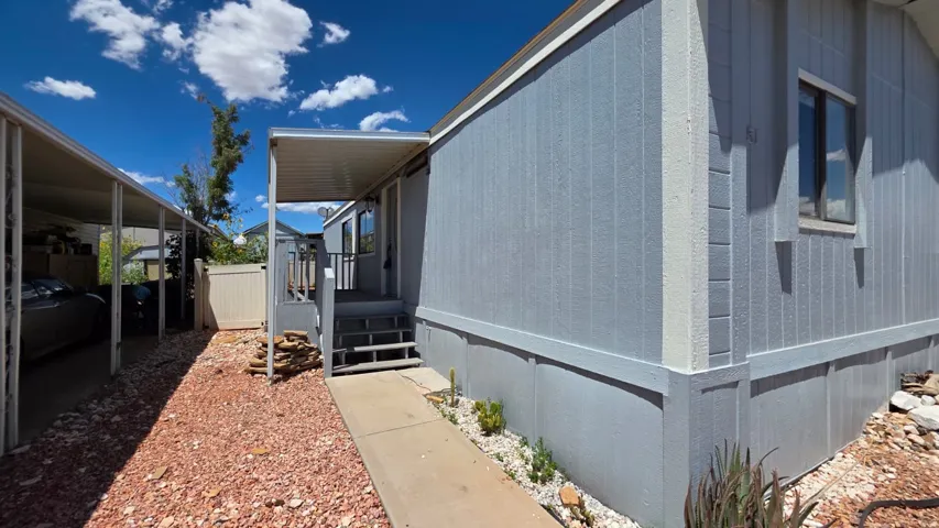 Light blue exterior siding with white trim, covered front entry, and a dedicated carport