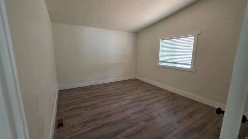 Room with wood-finish flooring, neutral wall paint, white trim, and a window with blinds