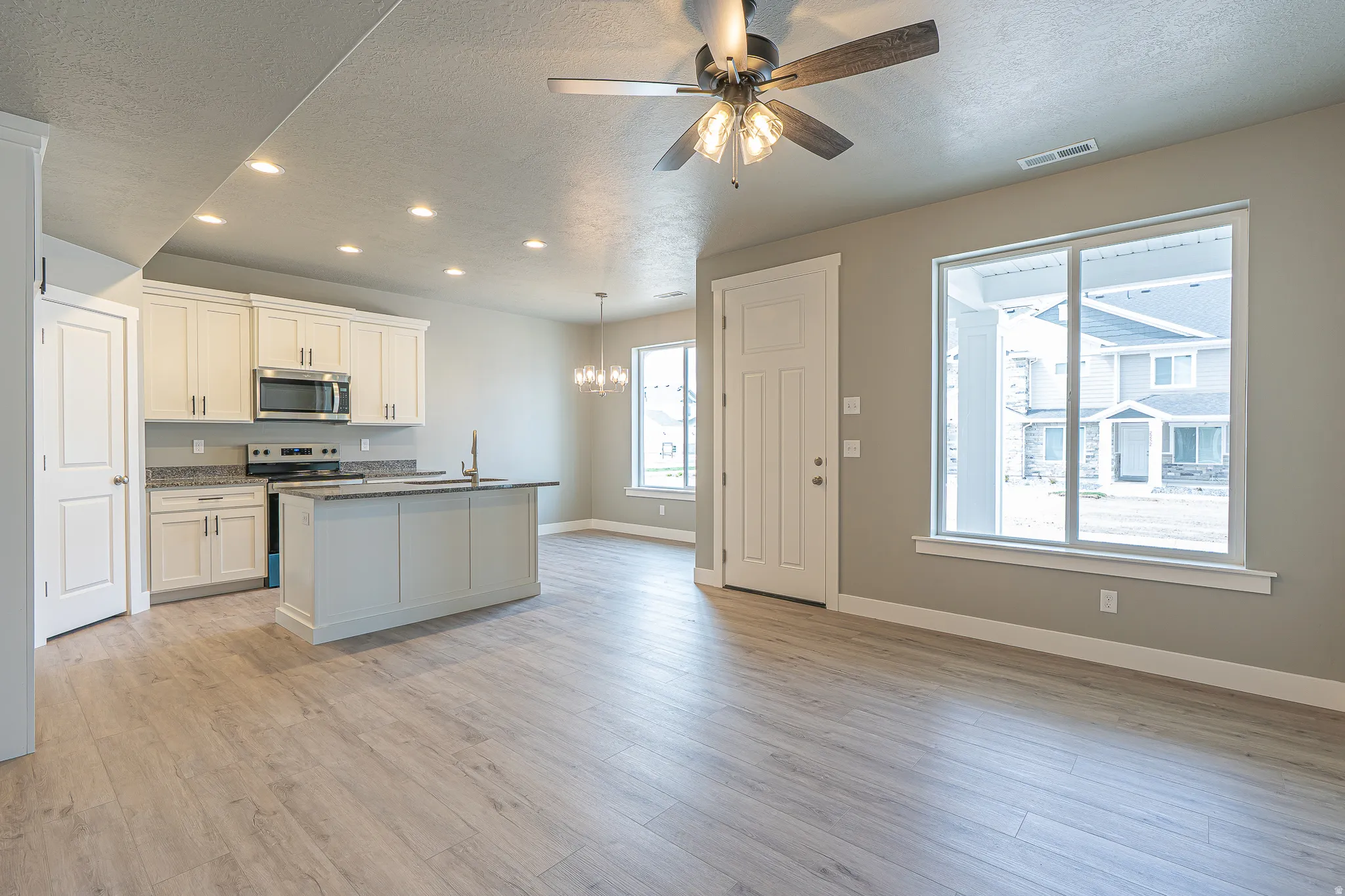 Open-concept living space with wood-finish flooring, recessed lighting, and a ceiling fan