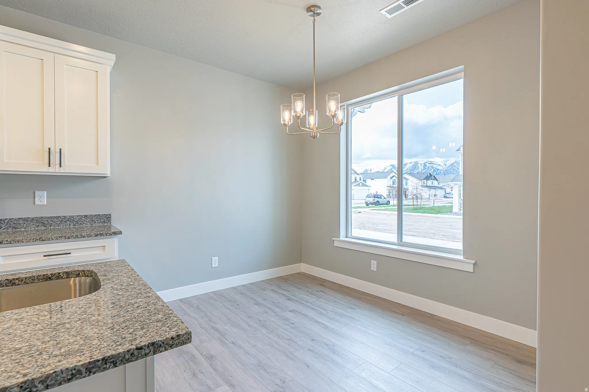 Kitchen area featuring white cabinetry, granite countertops, and a stainless steel sink