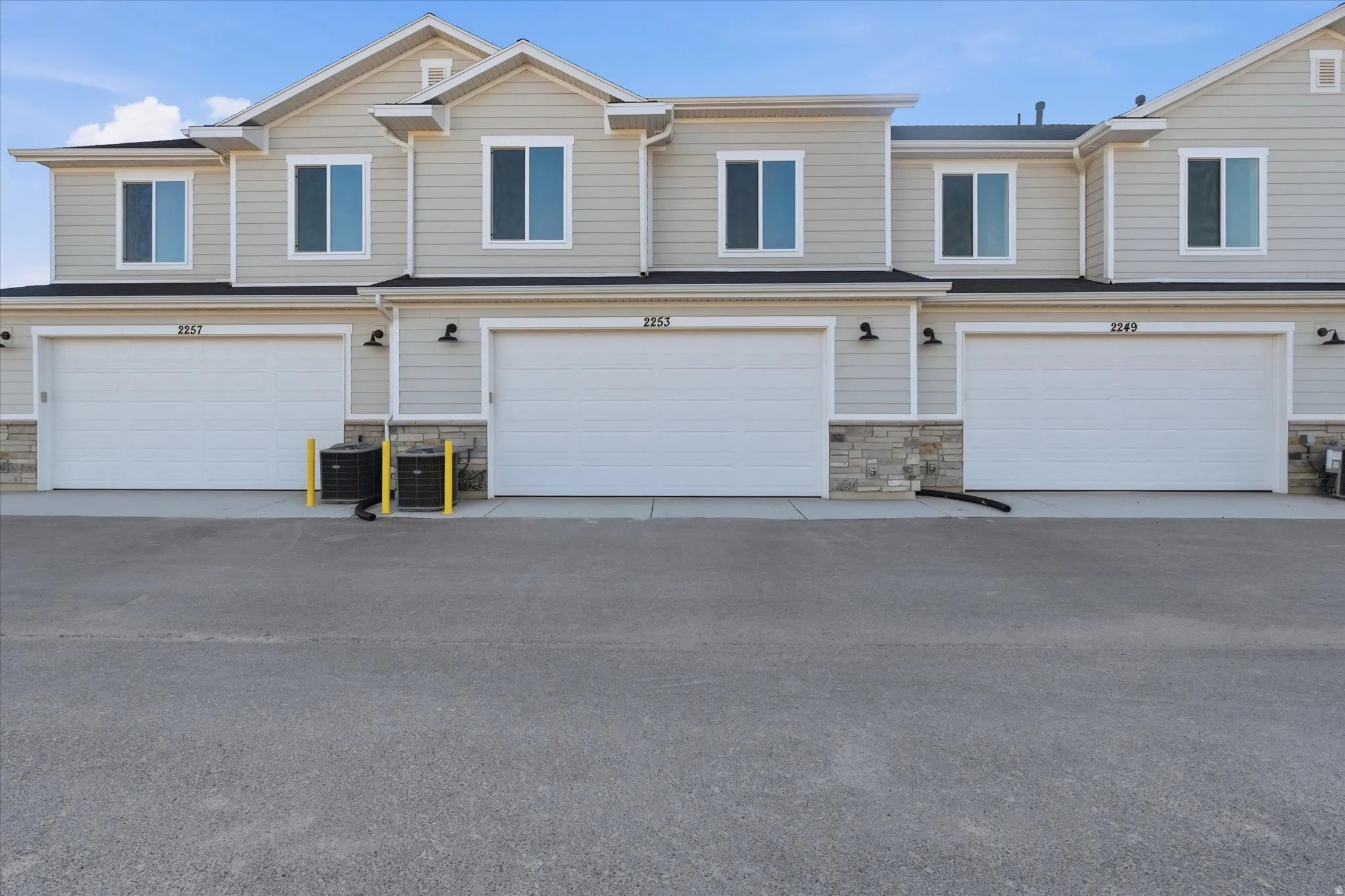 Townhome-style exterior featuring light-colored siding, dark trim, and a prominent gable roofline