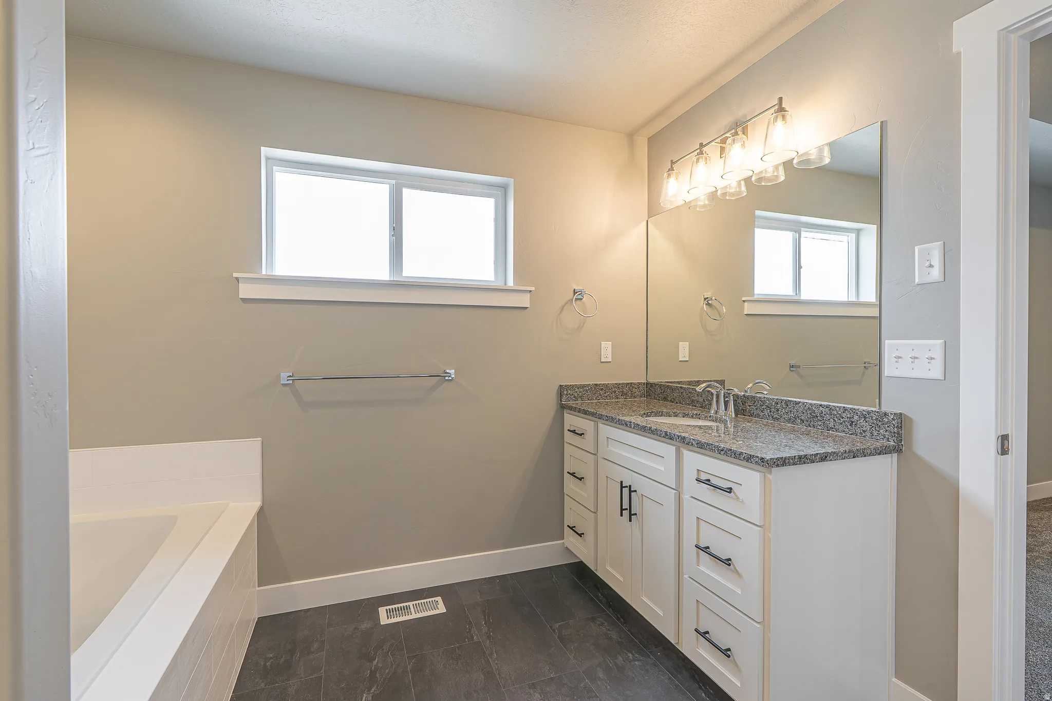 Bathroom featuring a white vanity with a granite countertop, a large mirror, and a modern light fixture