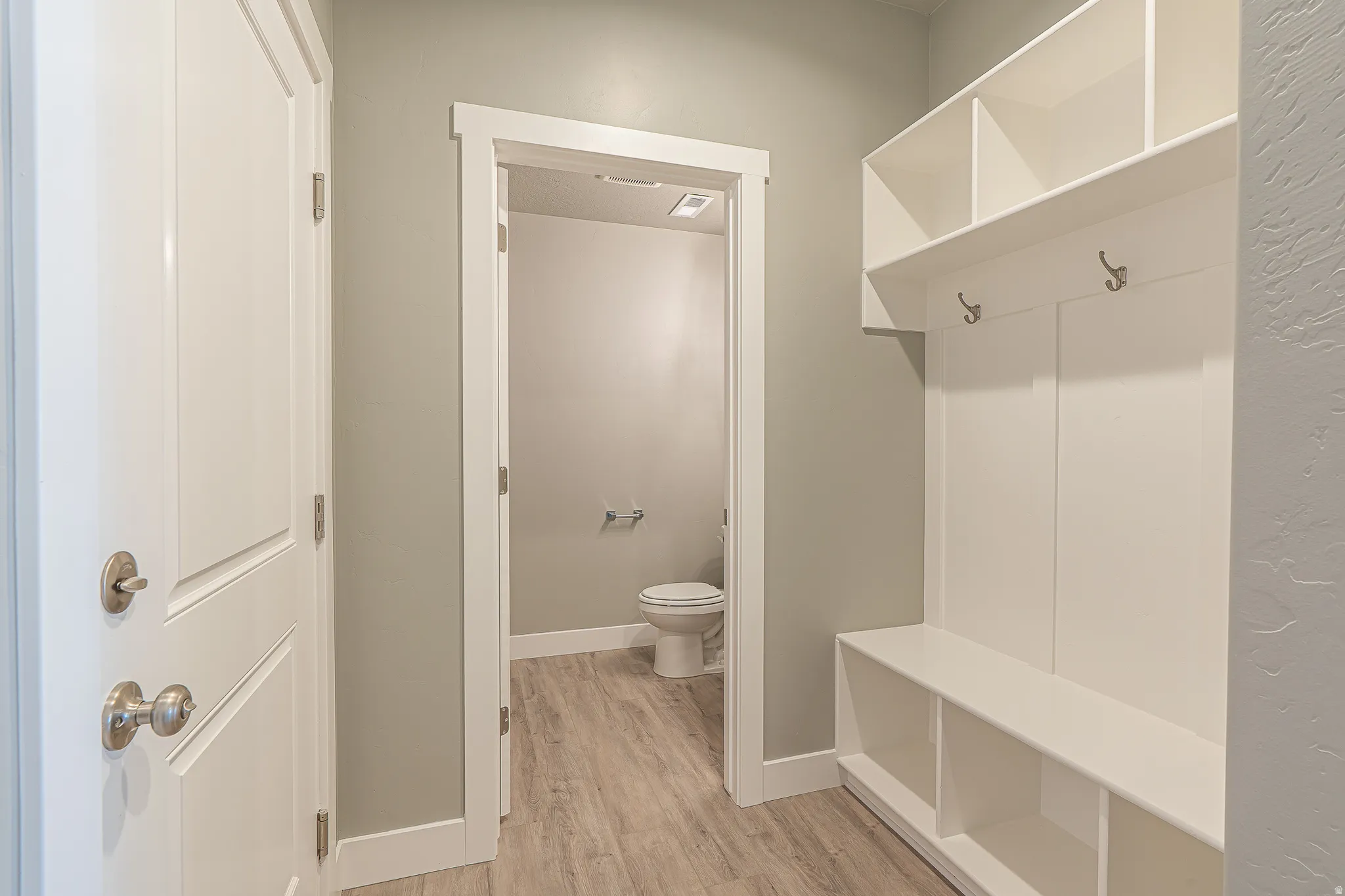 Entryway featuring a built-in mudroom bench with open cubbies, upper shelving, and coat hooks