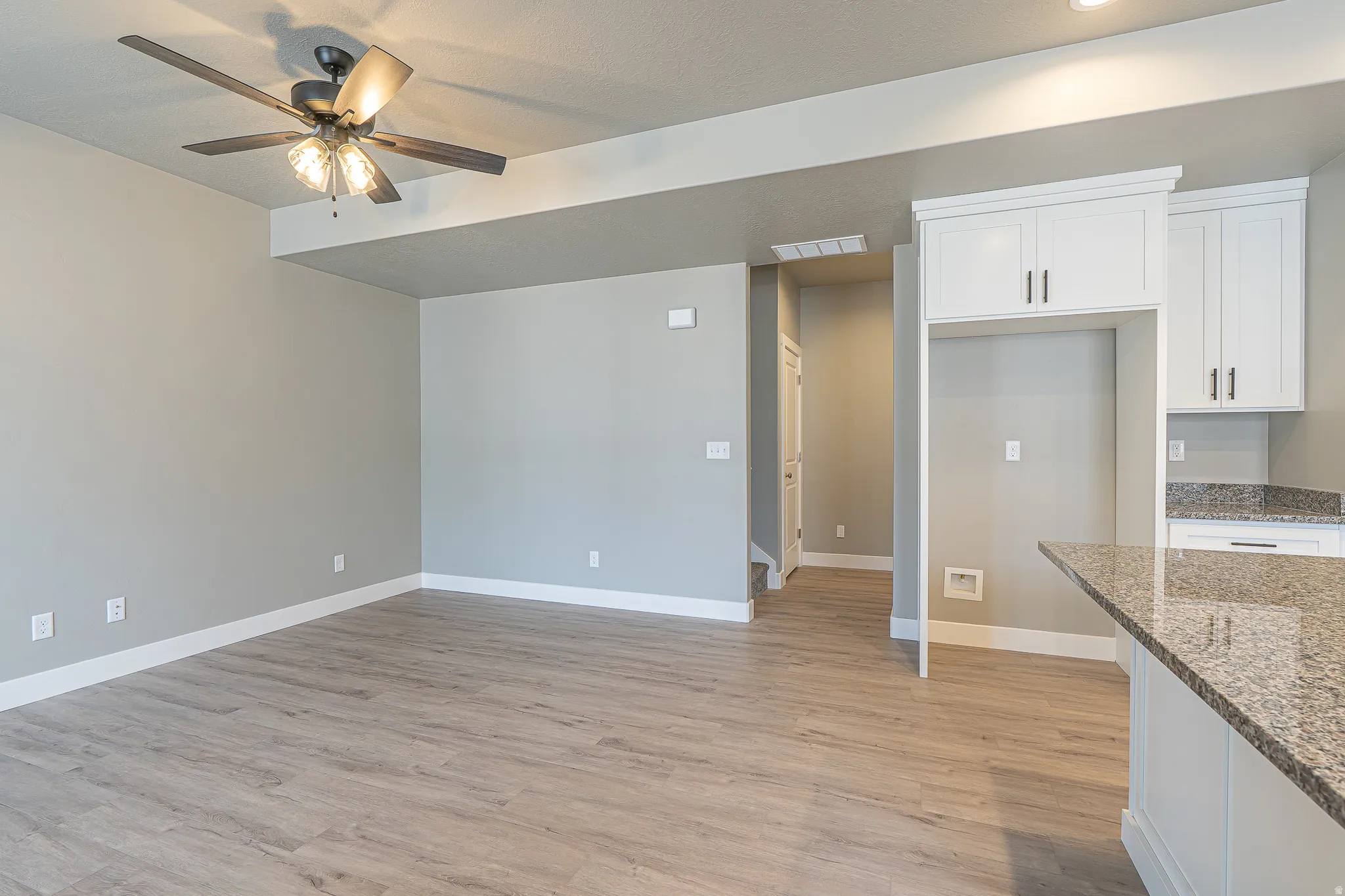 Open-concept living space featuring wood-finish flooring, a ceiling fan with integrated lighting, and recessed overhead lighting