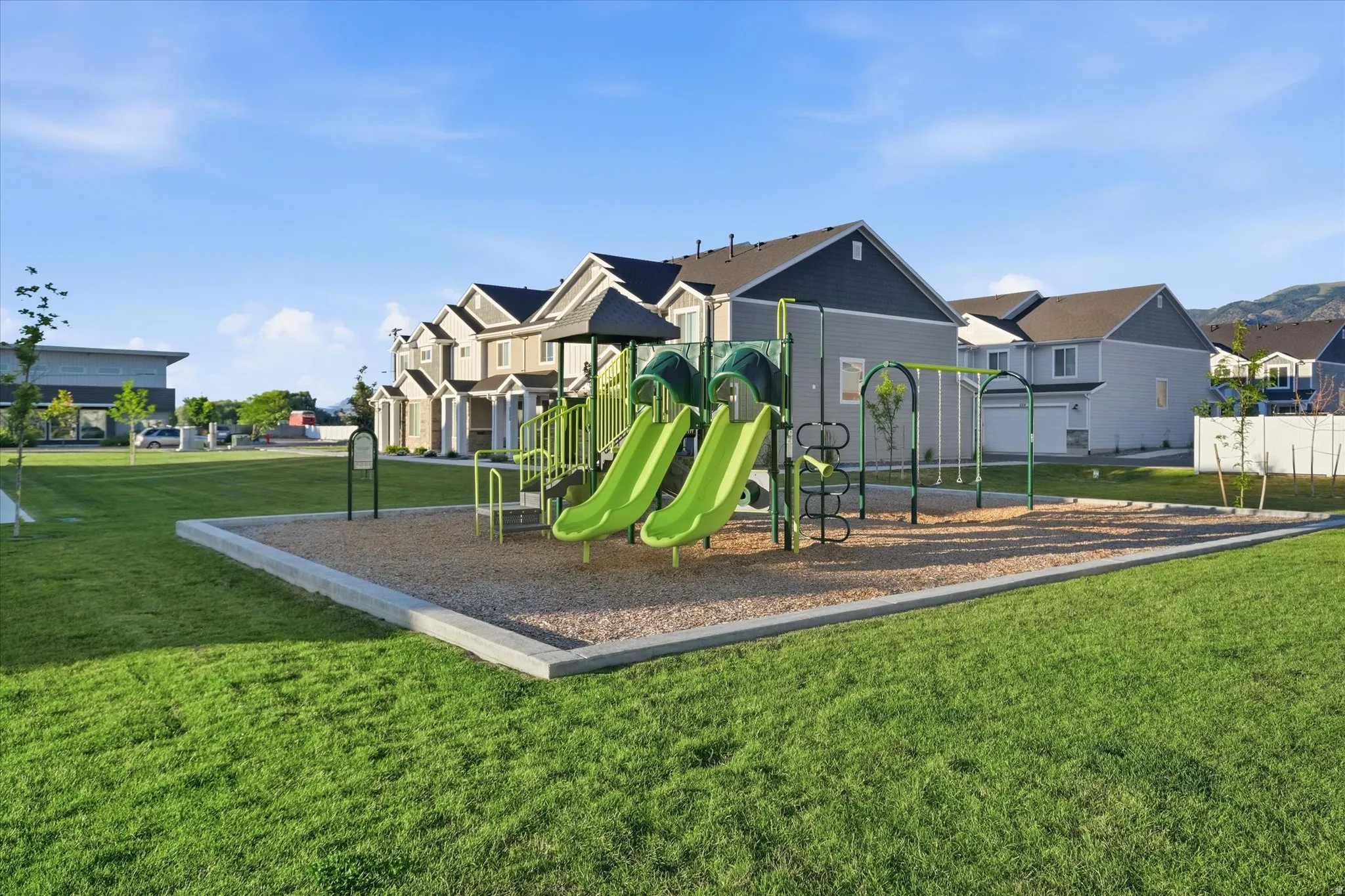 Community playground featuring multiple slides and swings on a gravel surface