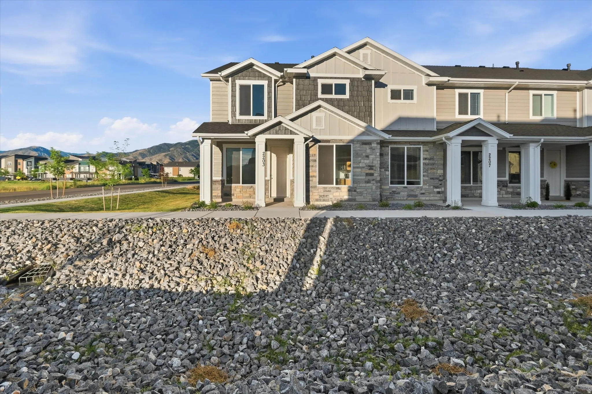 Contemporary townhome featuring a stone and siding facade, covered entryways, and multiple windows
