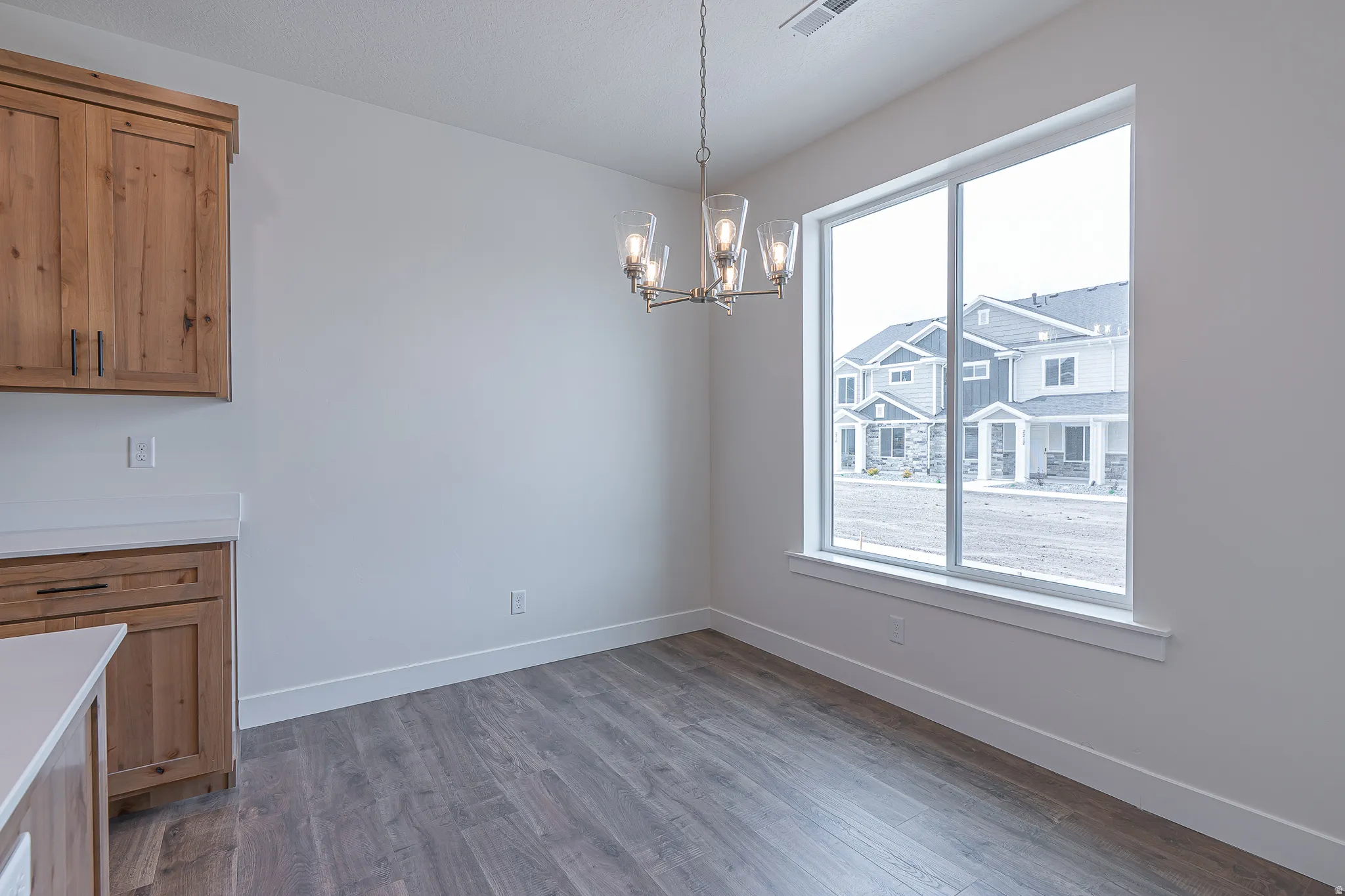 Dining space featuring wood-finish flooring, white walls, and a contemporary chandelier