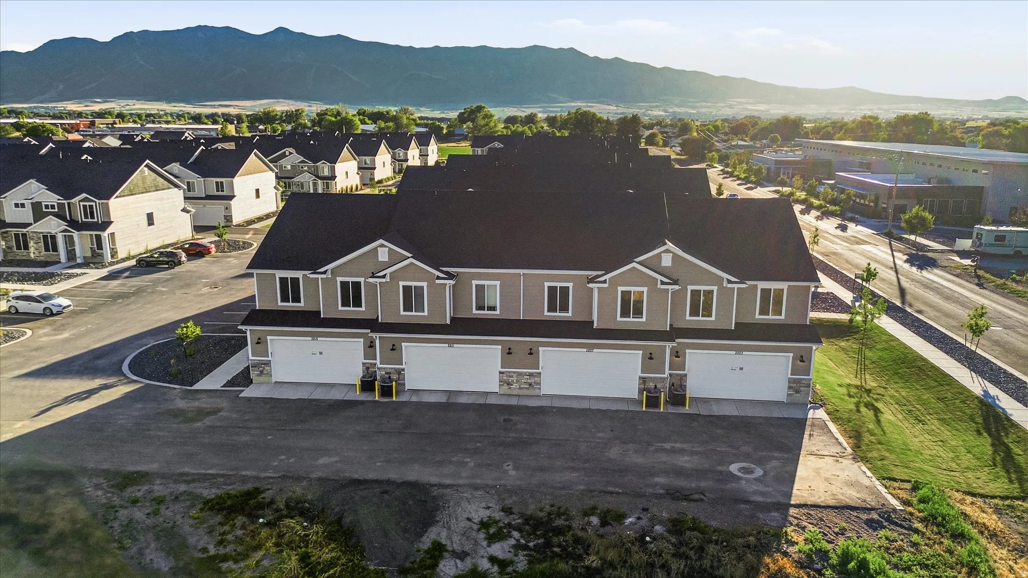 Modern townhome-style residences featuring neutral-toned siding, white garage doors, and stone facade accents