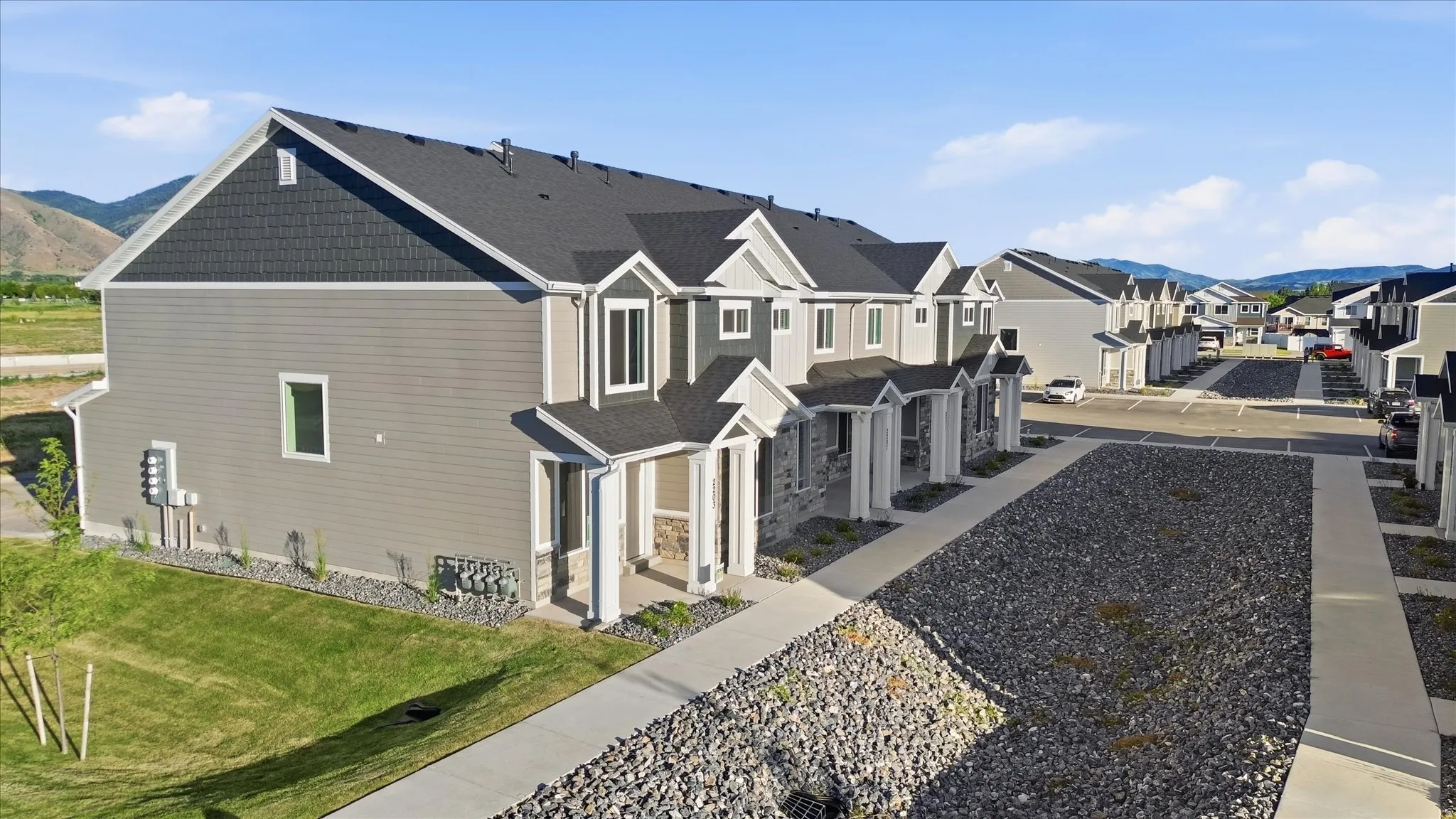 Modern townhome row featuring gray siding, dark shake siding accents, and gabled rooflines