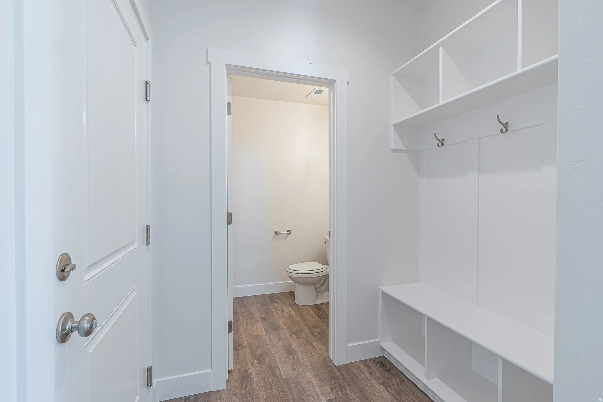 Built-in white storage bench with open shelving and coat hooks