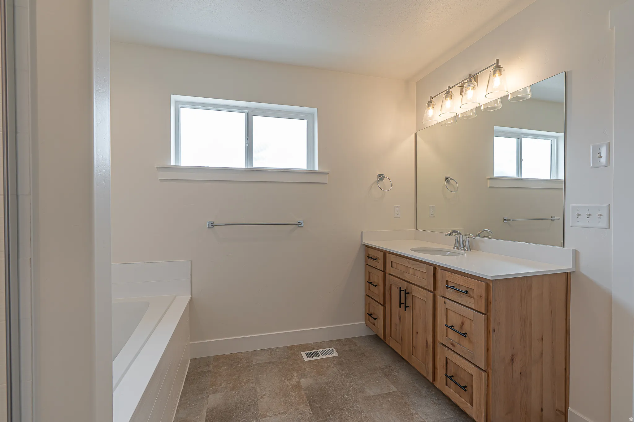 Bathroom featuring a light wood-finish vanity with a white countertop and an integrated sink, a rectangular mirror, and a five-light vanity fixture