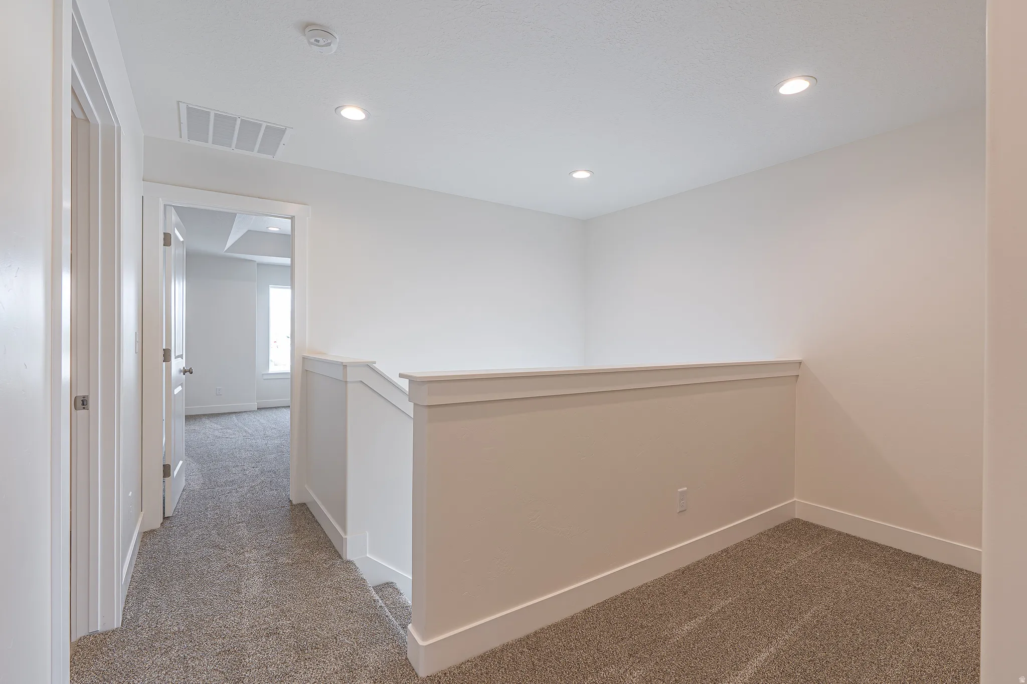 Loft area featuring neutral wall tones, recessed lighting, white trim, and textured carpeting
