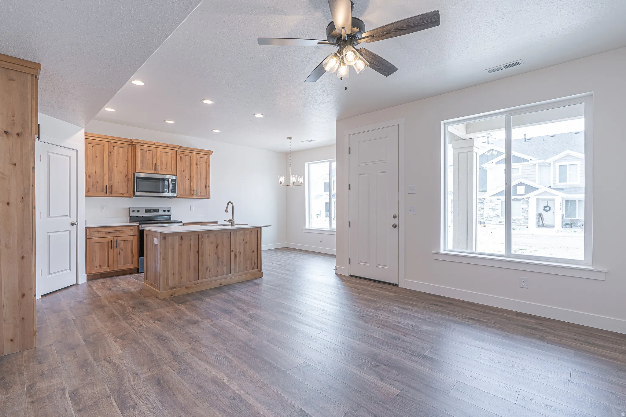 Open-concept living space featuring wood-finish flooring, recessed lighting, and a ceiling fan
