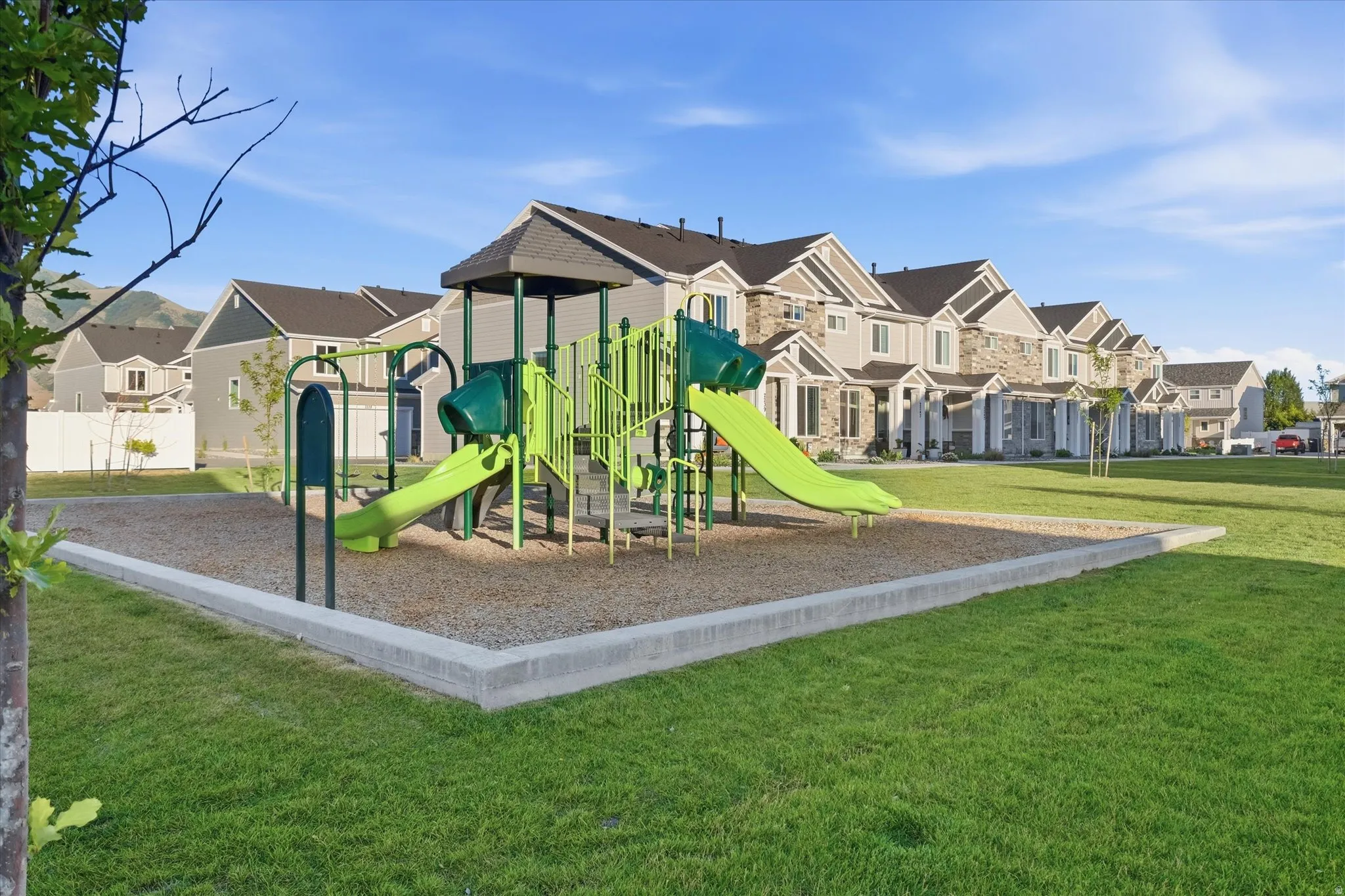 Community playground featuring a playset with slides and climbing structures, surrounded by a wood chip surface