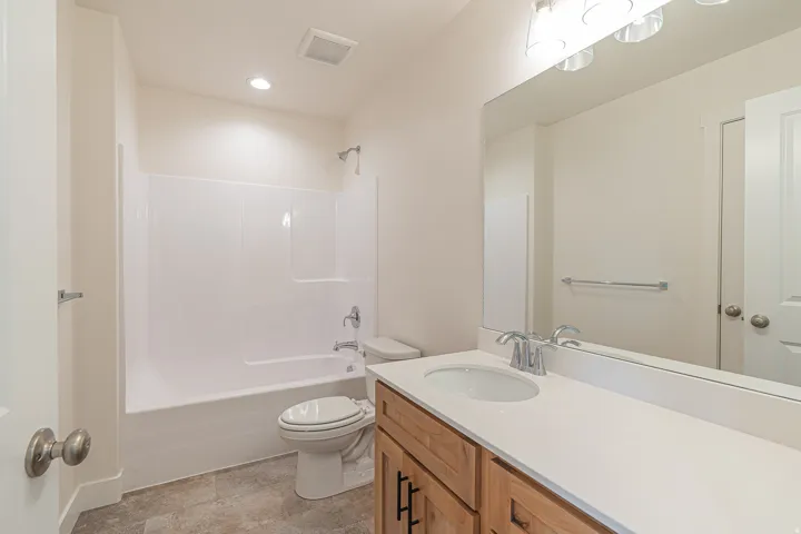 Full bathroom with a white tub and shower combination, chrome fixtures, and neutral-toned wall paint