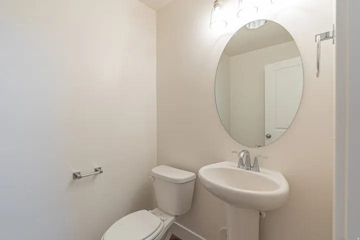 Pedestal sink with chrome faucet, an oval mirror, and a contemporary vanity light fixture