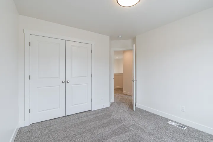Bright room featuring a flush-mount ceiling light, white walls, and light gray textured carpeting