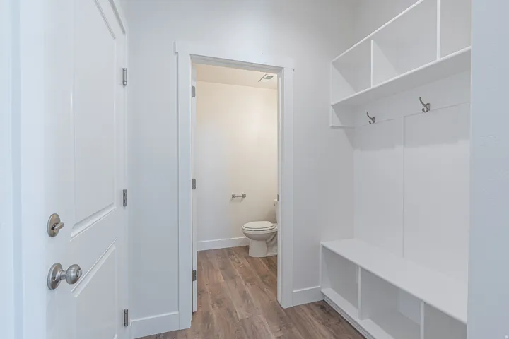 Built-in white storage bench with open shelving and coat hooks
