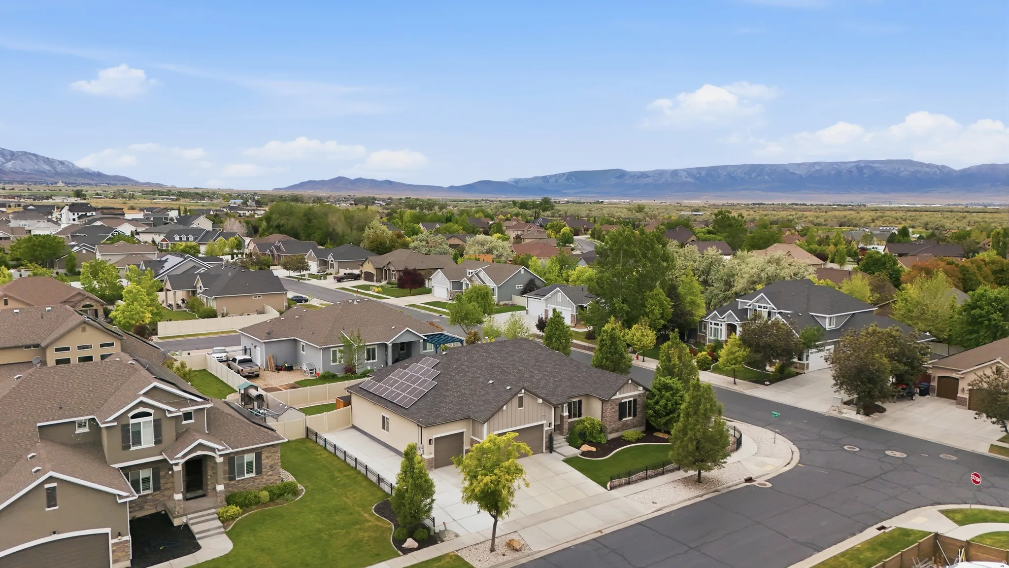 Residential neighborhood with diverse home styles, mature landscaping, and mountain scenery