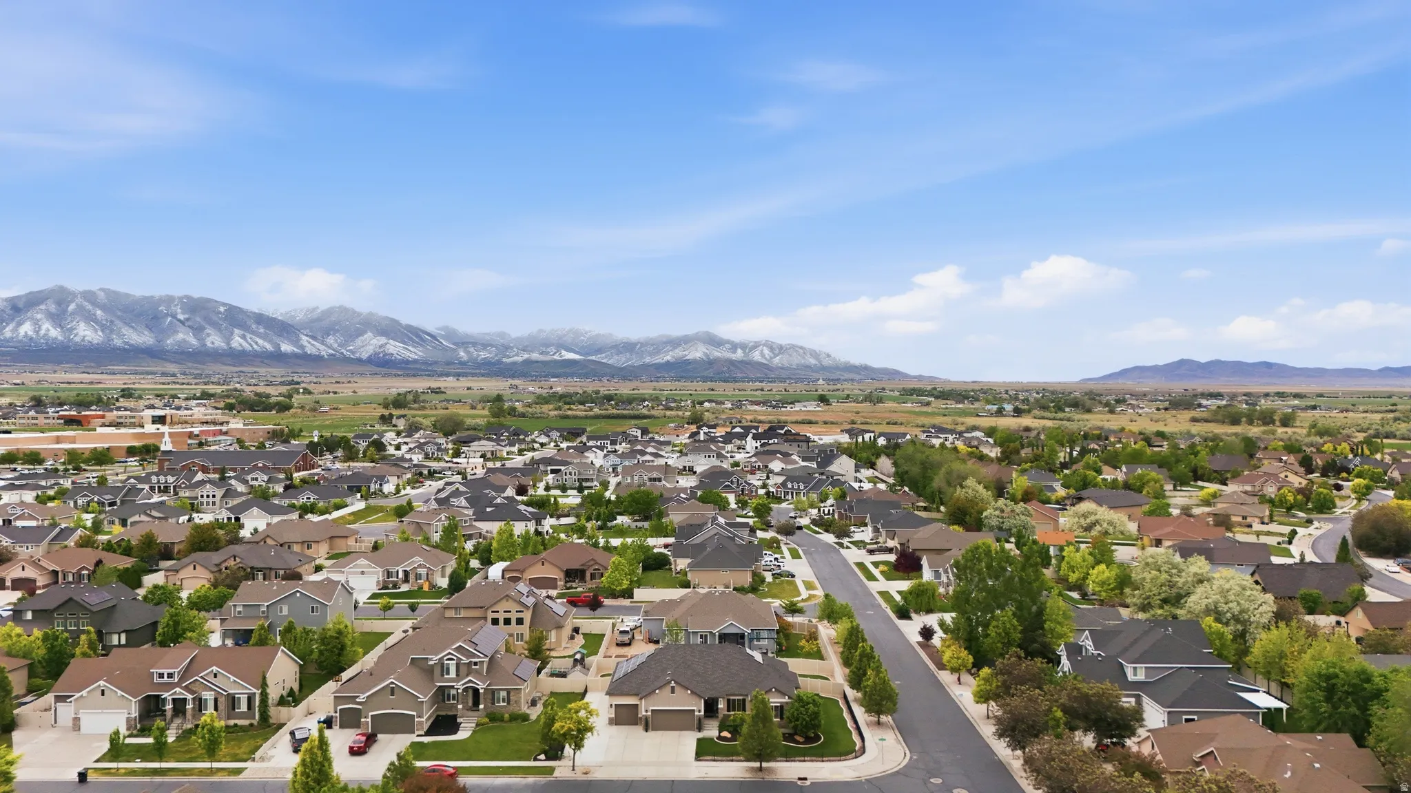 Expansive residential neighborhood with varied architectural styles, green landscaping, and distant snow-capped mountains